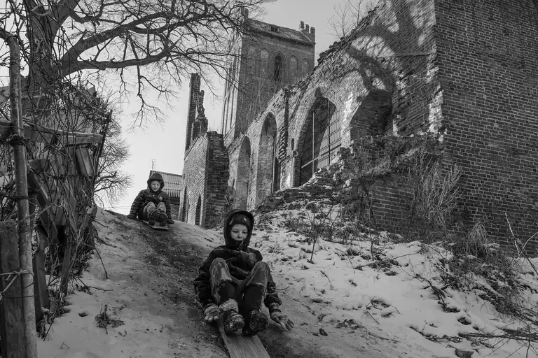 Children are sledding down a snowy hill near the church (1345) in Zheleznodorozhny (known as Gerdauen until 1945), Kaliningrad Region. Photo by Oleg Klimov