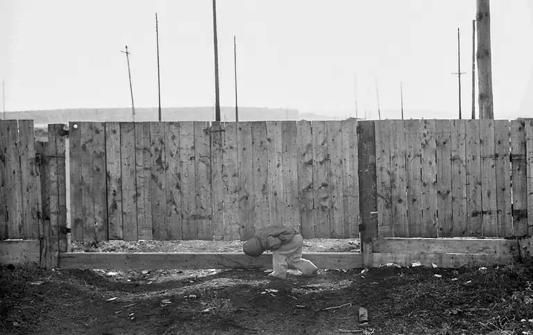 Through the gap in the fence, the boy can see the distant forest and geese walking along the street. Tisul village. Kemerovo region. Kuzbass. Siberia. 09/16/1983 Photo Vladimir Sokolaev/Liberty SU Archive