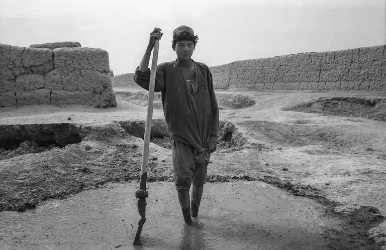 A man prepared a mixture for building a house in the desert. Northern Afghanistan, October, 2001. Photo by Oleg Klimov