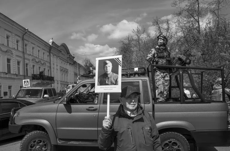 Victory Day Parade 2026. A participant in the “Immortal Regiment” march stands beside an anti-drone pickup truck fitted with counter-drone equipment and a stationary EW system. Yaroslavl, Russia’s Golden Ring, May 2026. Photo © Oleg Klimov for Panos Pictures.