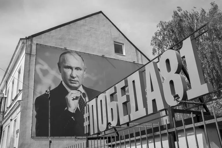 Portrait of Vladimir Putin on a government building and the tag #victory'